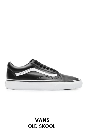 Tênis Vans modelo Old Skool na cor preta, com cadarços pretos, a clássica listra lateral branca e solado grosso de borracha branca, visto de perfil.